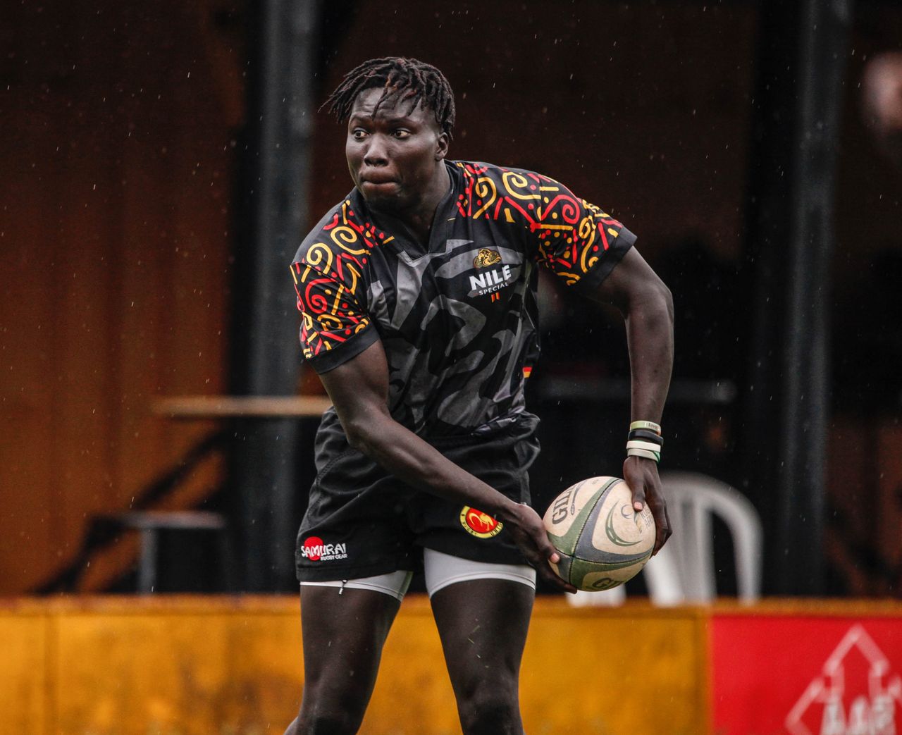 Athlete playing rugby in colorful sportswear during match outdoors.