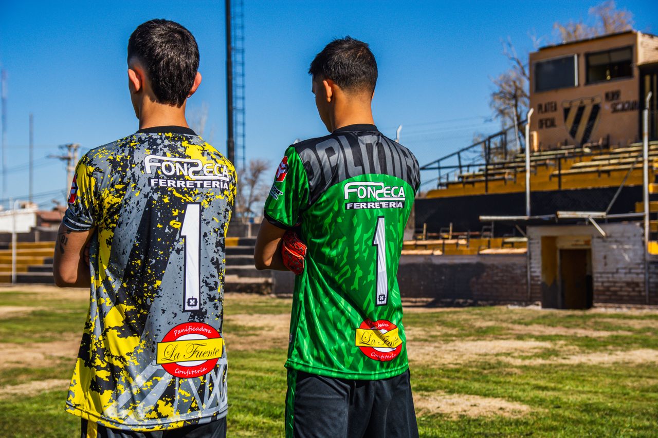 Two young soccer players in colorful jerseys, ready for a match on an urban field.