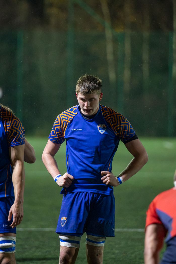 A focused rugby player during an intense night match on an English rugby field.