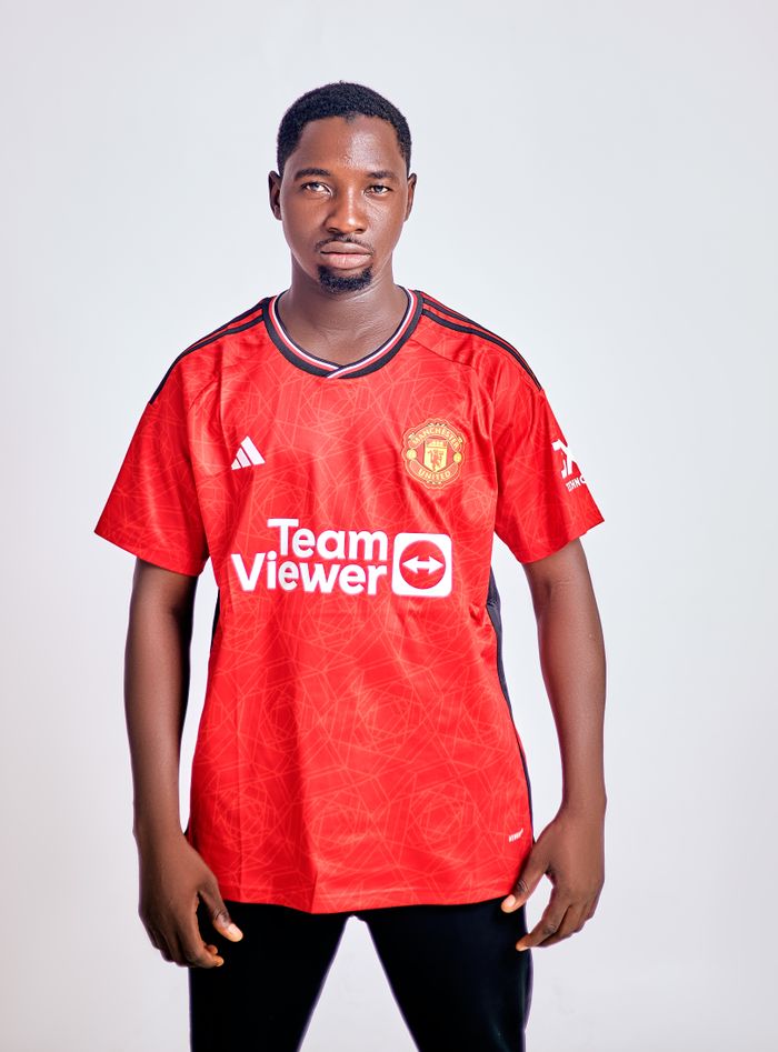 Young man wearing a red football jersey on a white background, isolated indoor portrait.