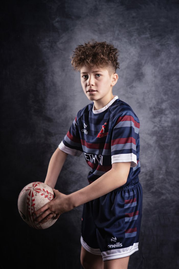Portrait of a young rugby player holding a ball in Manchester, capturing determination.