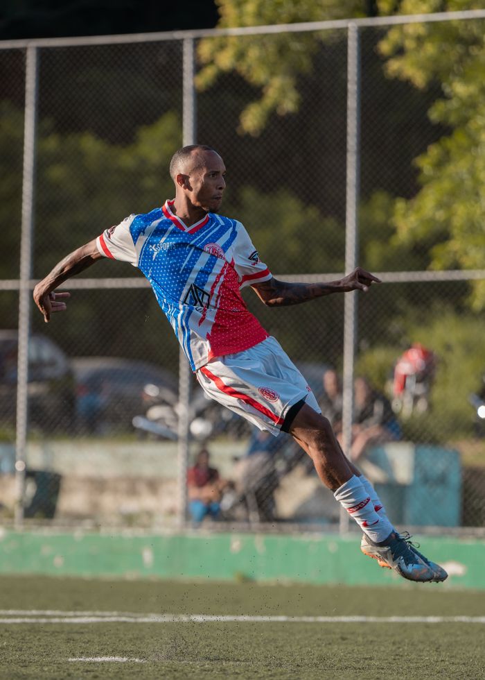 A soccer player in mid-air during an intense game on an outdoor field.