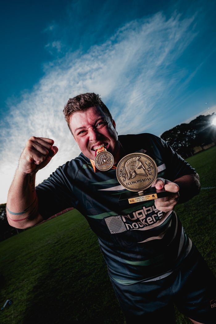 Enthusiastic rugby player celebrates with a medal in a vibrant outdoor setting.